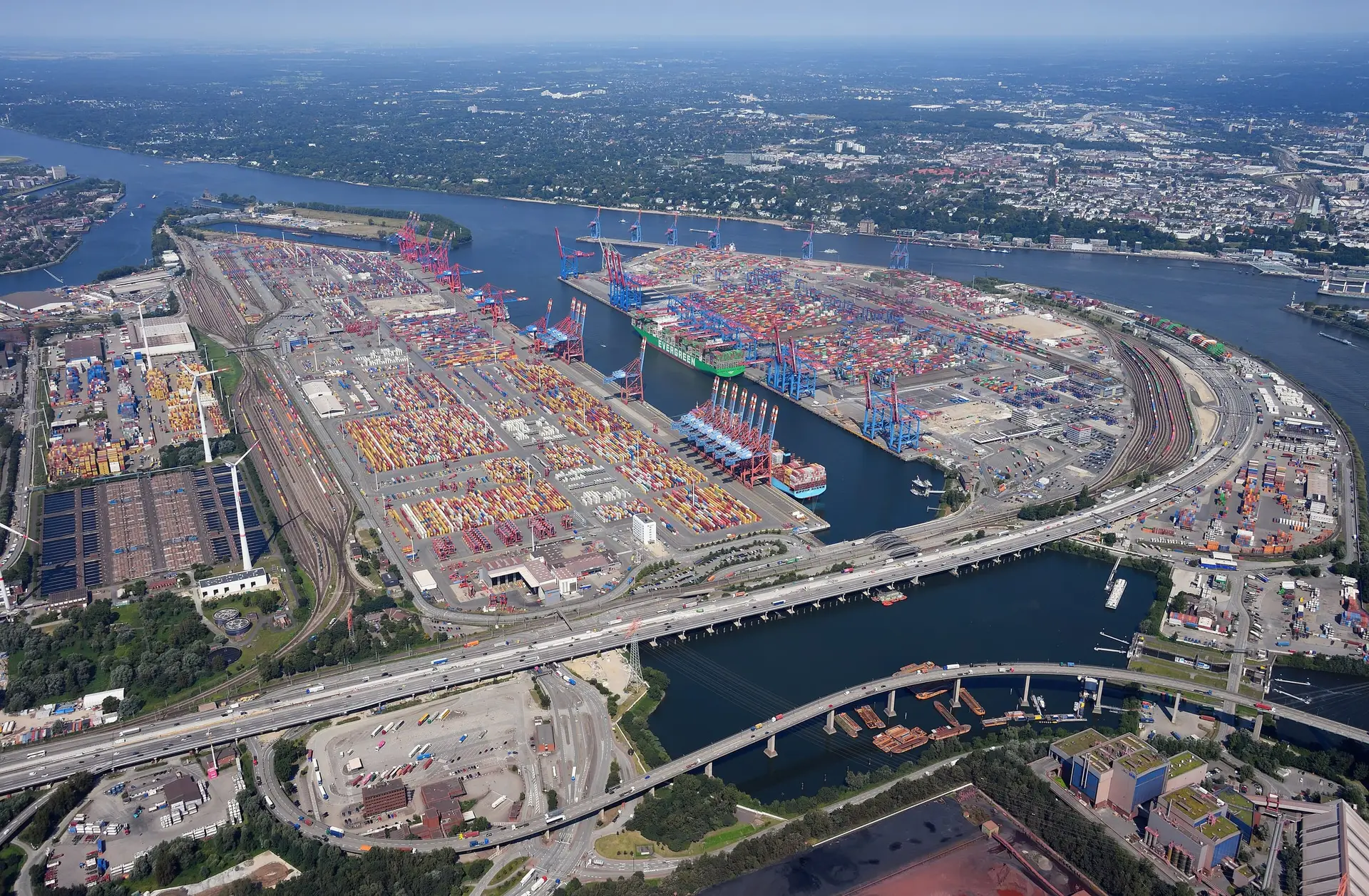 Container terminals in the Port of Hamburg from the air, with stacked containers and berthed ships beside the river.